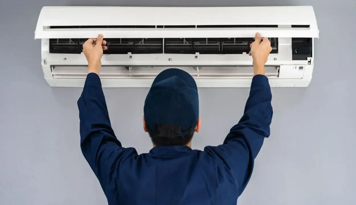 Tecnico apre il pannello di un condizionatore. Il motore esterno del condizionatore è pronto per la manutenzione.
