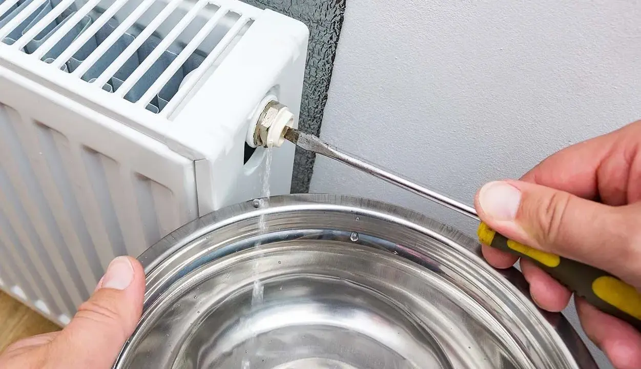 Si sta svuotando un termosifone per capire come è fatto all'interno. L'acqua esce da una valvola e cade in una bacinella.