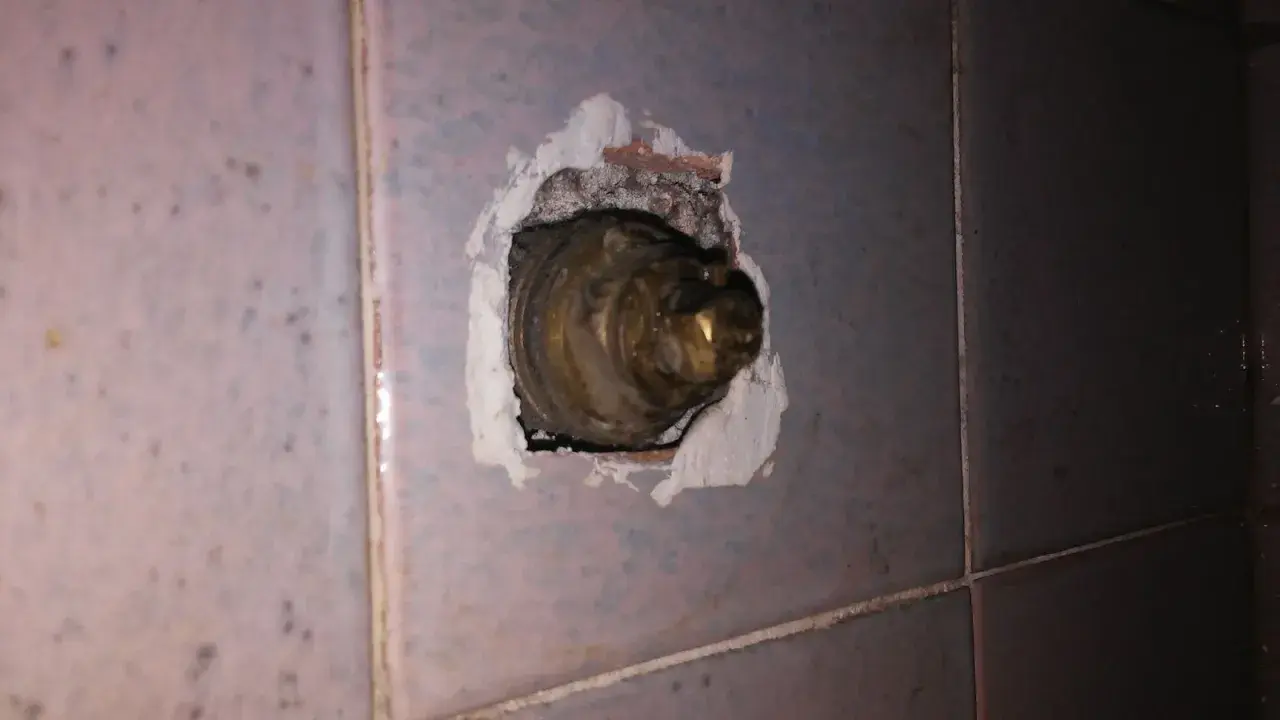 Parte interna di un rubinetto in ottone, incassato nel muro piastrellato. La chiusura del rubinetto acqua senso è necessaria per evitare perdite.
