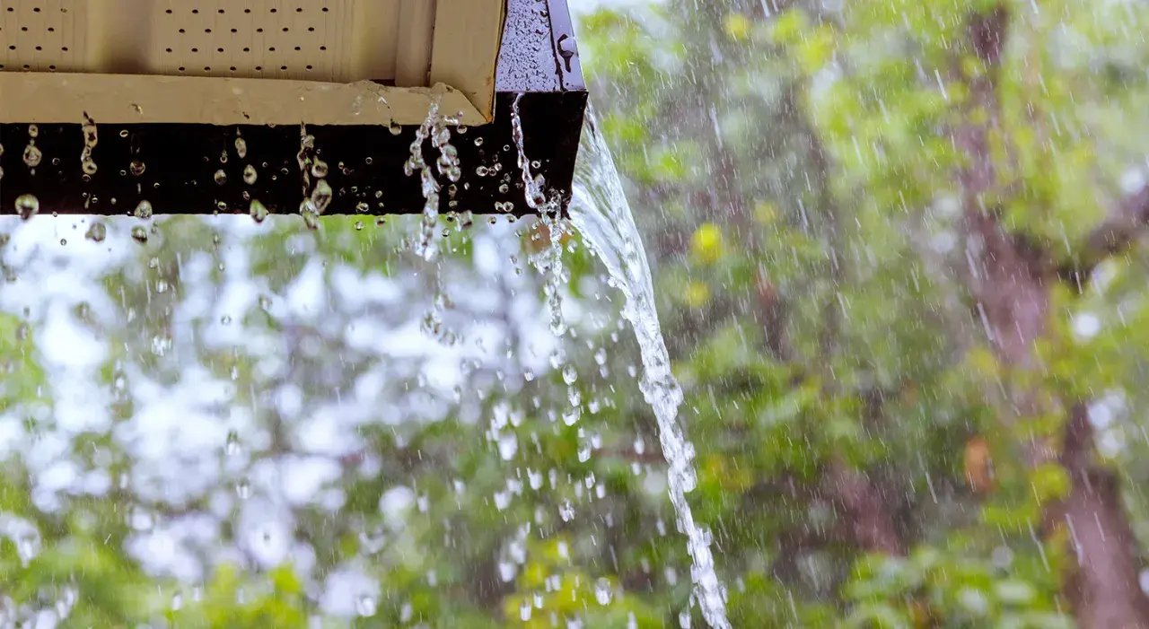 Acqua piovana che scorre da una grondaia, un esempio di impianto recupero acqua piovana pro e contro.