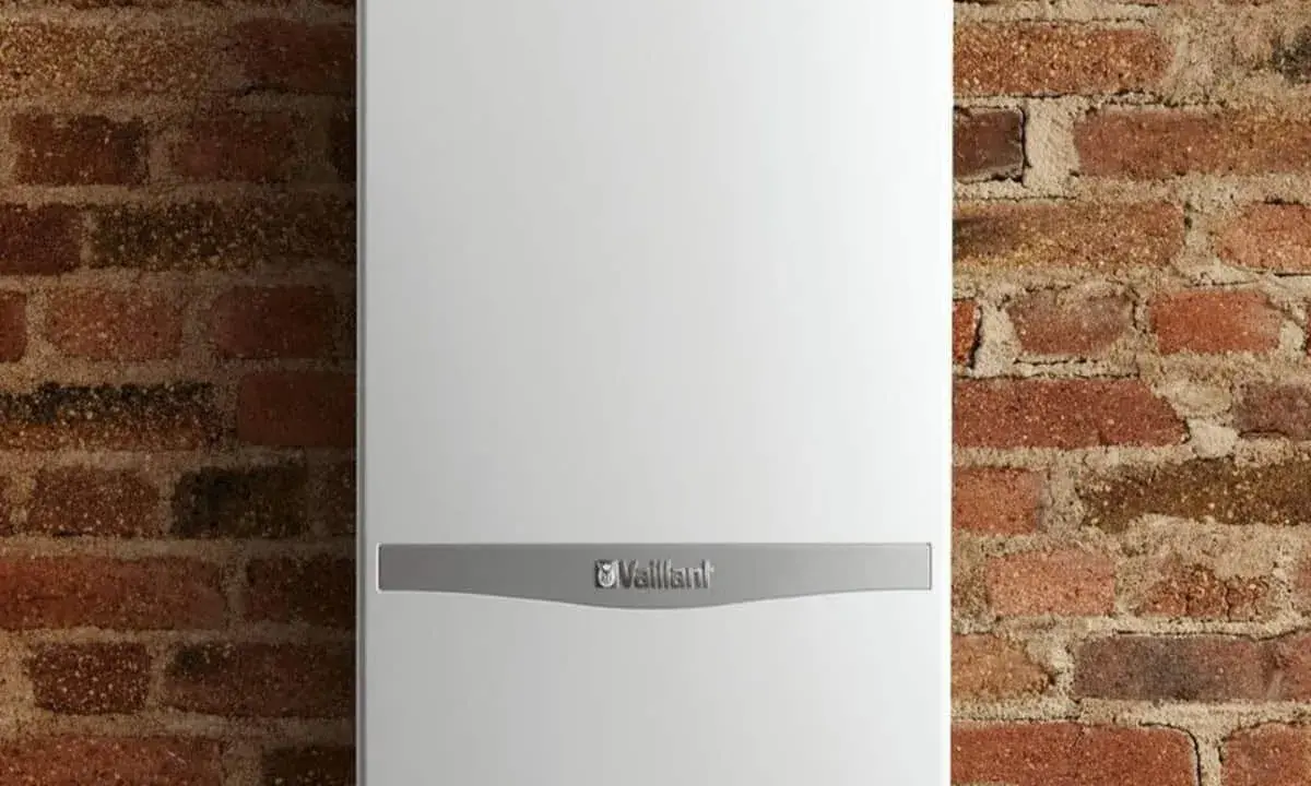 Caldaia Vaillant bianca, con logo, montata su parete in mattoni. Le dimensioni della caldaia sono compatte per adattarsi a spazi ridotti.