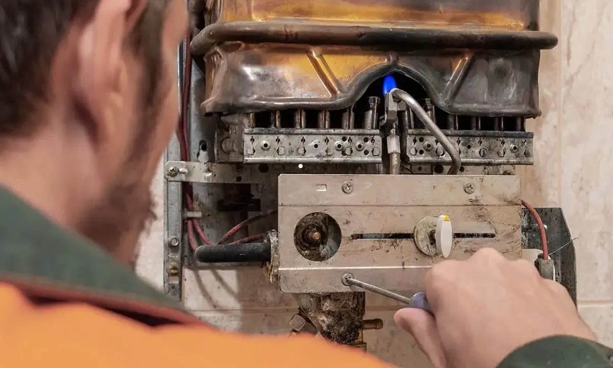 Tecnico ripara caldaia con fiamma blu, attenzione al monossido di carbonio. La caldaia è spenta.