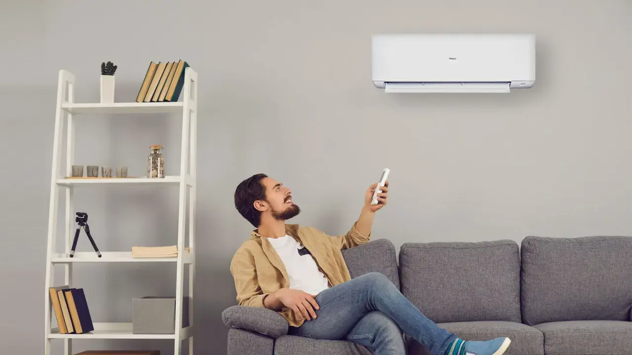 Uomo sorride usando telecomando per accendere un cool condizionatore. Il suo significato è comfort e benessere in casa.