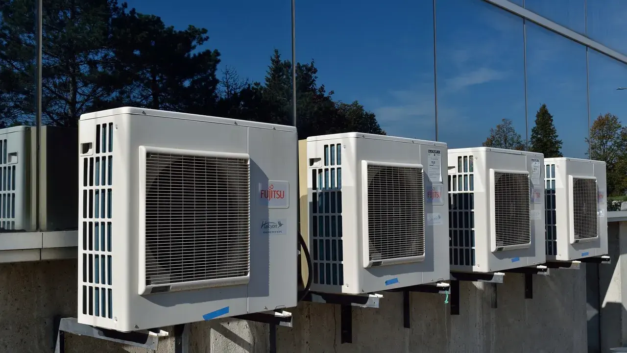 Unità esterne di condizionatori Fujitsu, montate su staffe, riflettono alberi e cielo. Il loro funzionamento è silenzioso, con un basso livello sonoro.