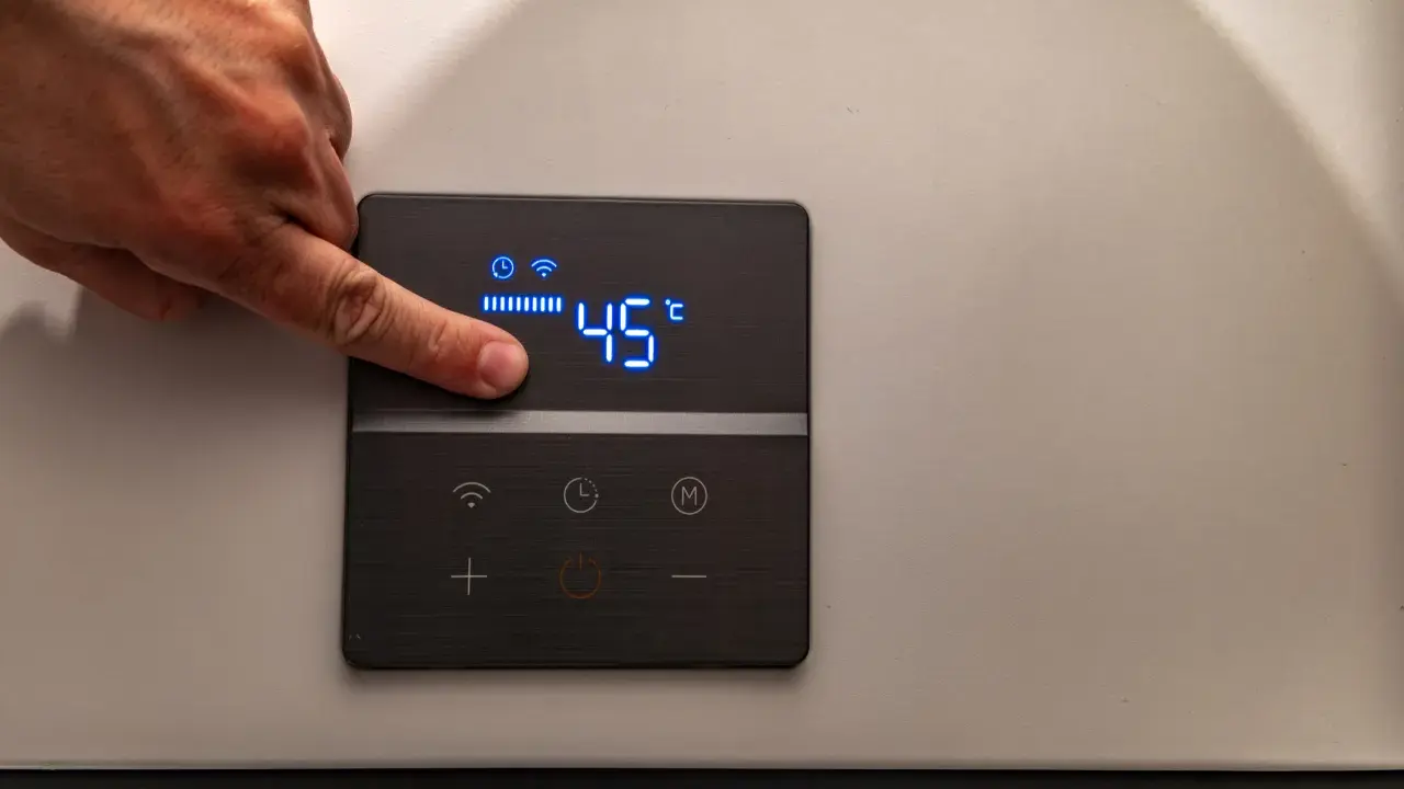 Dito un dito regola la temperatura su una caldaia elettrica a condensazione, impostata a 45°C.