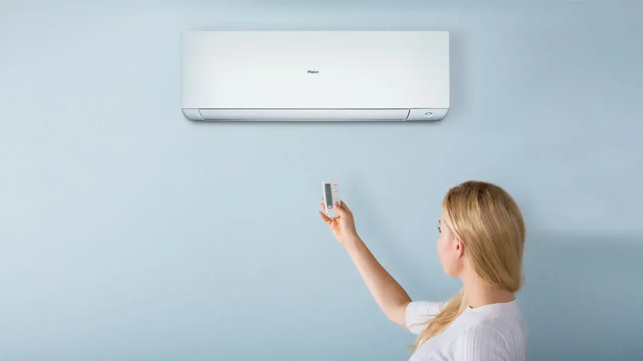 Donna usa il telecomando per regolare il condizionatore Haier. Il significato di "heat condizionatore" è la sua capacità di riscaldare.