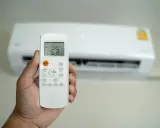 Mano che tiene un telecomando per condizionatore, impostato a 25°C. Il significato di "set temp condizionatore" è la temperatura desiderata.
