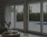 Soggiorno moderno con grandi vetrate che si affacciano su una piscina. L'isolamento acustico garantisce tranquillità.
