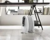 Un radiatore ad olio bianco, sotto una scrivania, mostra come funziona per riscaldare l'ambiente.
