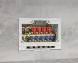 Installazione di collettori idraulici in un box a muro. Questi collettori, con valvole rosse e blu, sono essenziali per la distribuzione dell'acqua.