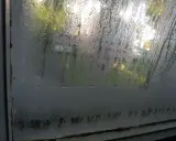Vetri appannati: un segnale che è ora di capire come misurare umidità in casa. Goccioline d'acqua sul vetro riflettono la luce esterna.