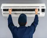 Tecnico apre il pannello di un condizionatore. Il motore esterno del condizionatore è pronto per la manutenzione.