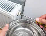 Si sta svuotando un termosifone per capire come è fatto all'interno. L'acqua esce da una valvola e cade in una bacinella.