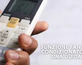 Mano che tiene un telecomando per il condizionatore, con il tasto "FAN" visibile. Guida alla funzione fan del condizionatore.