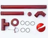 Schema corretto montaggio tubi stufa a pellet: componenti in metallo rosso scuro, tra cui tubi dritti, un raccordo a T, un gomito, tappi, guarnizioni e un supporto a muro.
