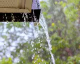 Acqua piovana che scorre da una grondaia, un esempio di impianto recupero acqua piovana pro e contro.