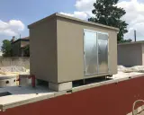 Edificio prefabbricato con porte metalliche, probabilmente per ospitare una pompa soprabattente, su una base in cemento.