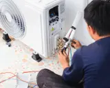 Tecnico che effettua la manutenzione condizionatori, collegando i tubi all'unità esterna.