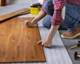 Persona posiziona assi di legno su un tappetino isolante, un passo fondamentale per come insonorizzare il pavimento e ridurre i rumori.