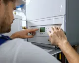 Tecnico che controlla il display della caldaia in blocco, impostando la temperatura.