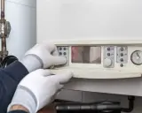 Mani guantate impostano un pannello di controllo, forse per capire la differenza tra caldaia e scaldabagno.