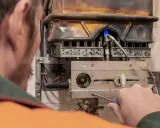 Tecnico ripara caldaia con fiamma blu, attenzione al monossido di carbonio. La caldaia è spenta.