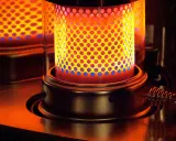 La stufa a kerosene pericolosa emana un calore intenso, con fiamme blu e gialle che danzano attraverso la griglia forata.