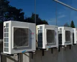 Unità esterne di condizionatori Fujitsu, montate su staffe, riflettono alberi e cielo. Il loro funzionamento è silenzioso, con un basso livello sonoro.