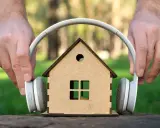 Mani posizionano cuffie su una casa giocattolo, come se volessero ascoltare suoni a 110 decibel.