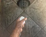 Mano che tiene una saponetta sotto la doccia, con getti d'acqua che suggeriscono il desiderio di aumentare pressione acqua doccia.
