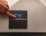 Dito un dito regola la temperatura su una caldaia elettrica a condensazione, impostata a 45°C.