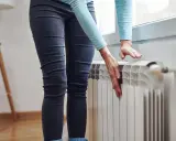 Mani che controllano un termosifone freddo, preoccupazione per il riscaldamento che non funziona.