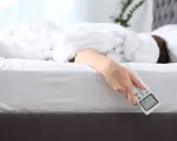 Mano che tiene il telecomando del condizionatore, con la persona che cerca il **significato** di un **sonno** confortevole.