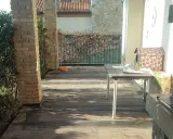 Terrazzo con pavimentazione scura, ideale per l'impermeabilizzazione. Tavolo, barbecue e vegetazione completano la scena.