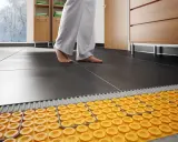 Il collettore termosifoni come funziona: un sistema di riscaldamento a pavimento con tubi gialli sotto le piastrelle scure.