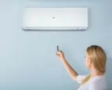 Donna usa il telecomando per regolare il condizionatore Haier. Il significato di "heat condizionatore" è la sua capacità di riscaldare.