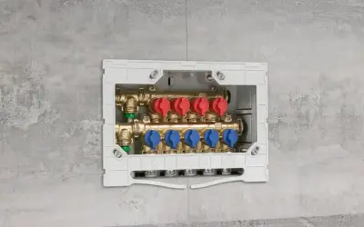 Installazione di collettori idraulici in un box a muro. Questi collettori, con valvole rosse e blu, sono essenziali per la distribuzione dell'acqua.