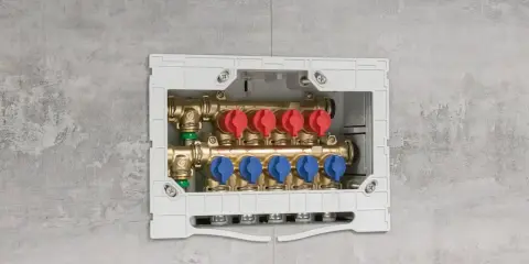Installazione di collettori idraulici in un box a muro. Questi collettori, con valvole rosse e blu, sono essenziali per la distribuzione dell'acqua.