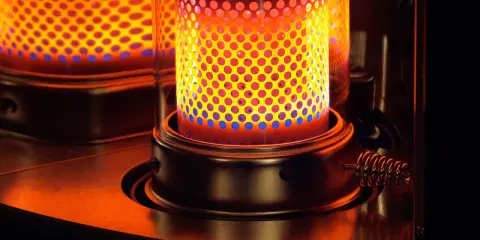 La stufa a kerosene pericolosa emana un calore intenso, con fiamme blu e gialle che danzano attraverso la griglia forata.