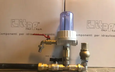 Componenti idraulici in ottone con filtro e rubinetto, parte di un sistema a pompa a colpo d'ariete.