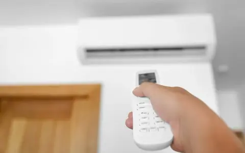 Mano che regola la temperatura condizionatore con telecomando.