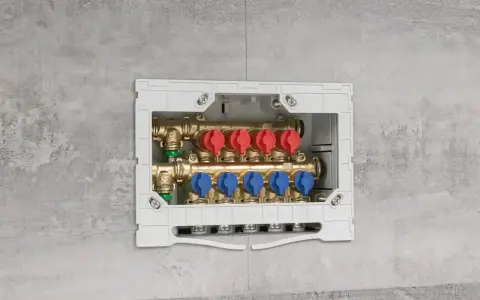 Installazione di collettori idraulici in un box a muro. Questi collettori, con valvole rosse e blu, sono essenziali per la distribuzione dell'acqua.