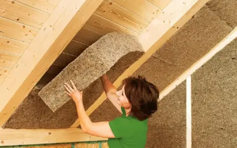 Donna installa pannelli isolanti in fibra di legno, il miglior isolante termico per soffitto, per un tetto efficiente.