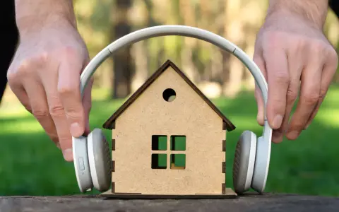 Mani posizionano cuffie su una casa giocattolo, come se volessero ascoltare suoni a 110 decibel.