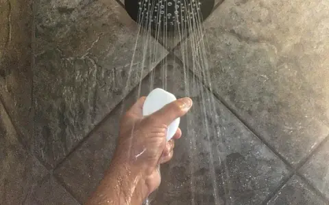 Mano che tiene una saponetta sotto la doccia, con getti d'acqua che suggeriscono il desiderio di aumentare pressione acqua doccia.