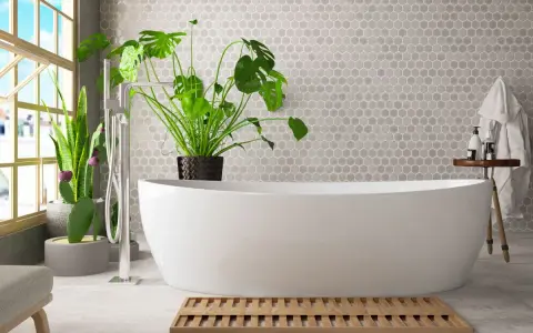 Un bagno umido cosa fare? Una vasca bianca, piante verdi e un tappetino in legno.