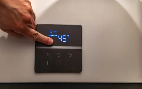 Dito un dito regola la temperatura su una caldaia elettrica a condensazione, impostata a 45°C.