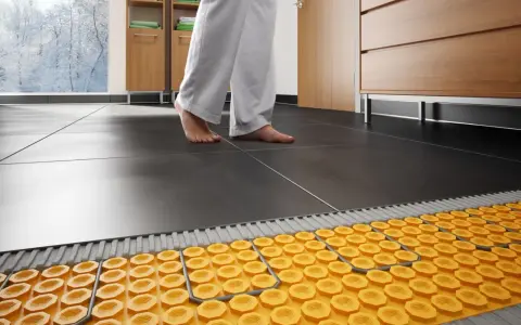 Il collettore termosifoni come funziona: un sistema di riscaldamento a pavimento con tubi gialli sotto le piastrelle scure.