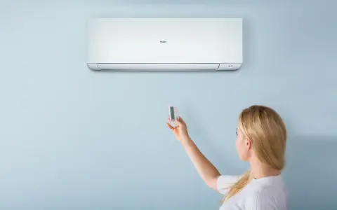 Donna usa il telecomando per regolare il condizionatore Haier. Il significato di "heat condizionatore" è la sua capacità di riscaldare.