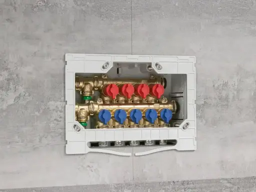 Installazione di collettori idraulici in un box a muro. Questi collettori, con valvole rosse e blu, sono essenziali per la distribuzione dell'acqua.